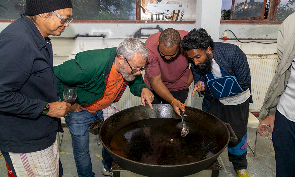 Participants at the Gasthof symposium bend over a paella pan